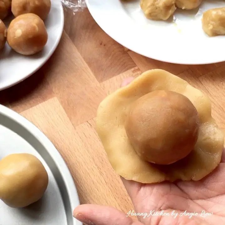 Wrap the filling ball with mooncake dough.