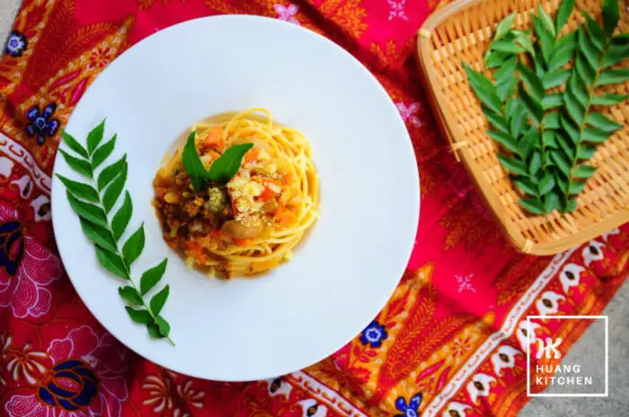 Spaghetti with Curry Meat Sauce (Malaysian Style Bolognese Pasta) Recipe by Huang Kitchen - Top down view of pasta with tray of curry leaves batik background
