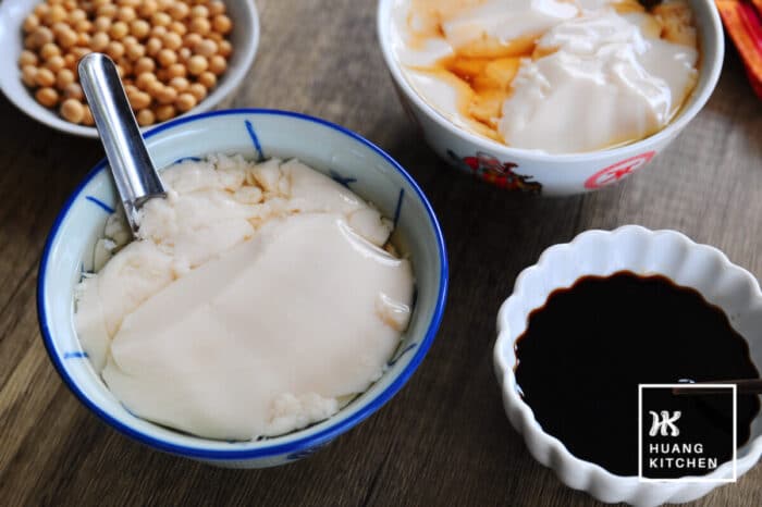 Tau Foo Fah Recipe (Douhua / Soybean Pudding) Recipe by Huang Kitchen - served with ginger syrup or palm sugar Gula Melaka Syrup side view with blue bowl and metal spoon soybeans